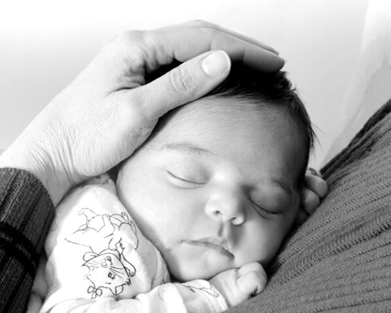 Neonato che dorme tra le braccia sicure della mamma